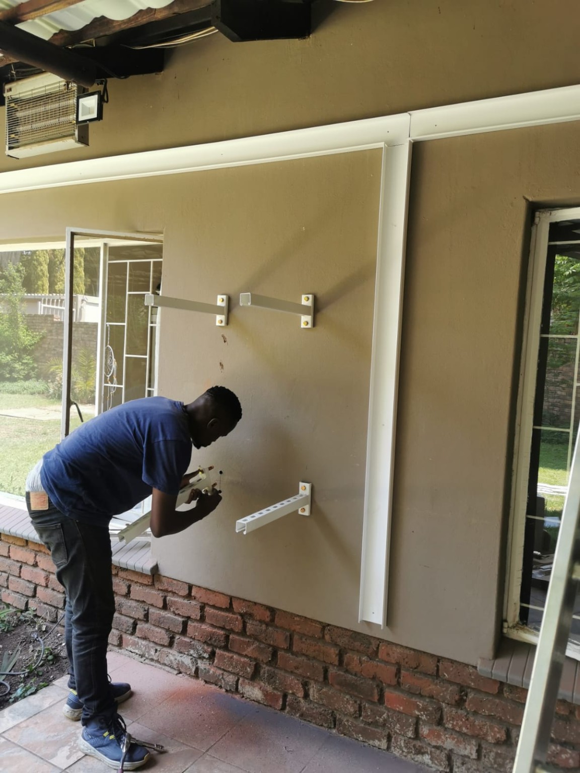 Technician fitting air conditioning support brackets